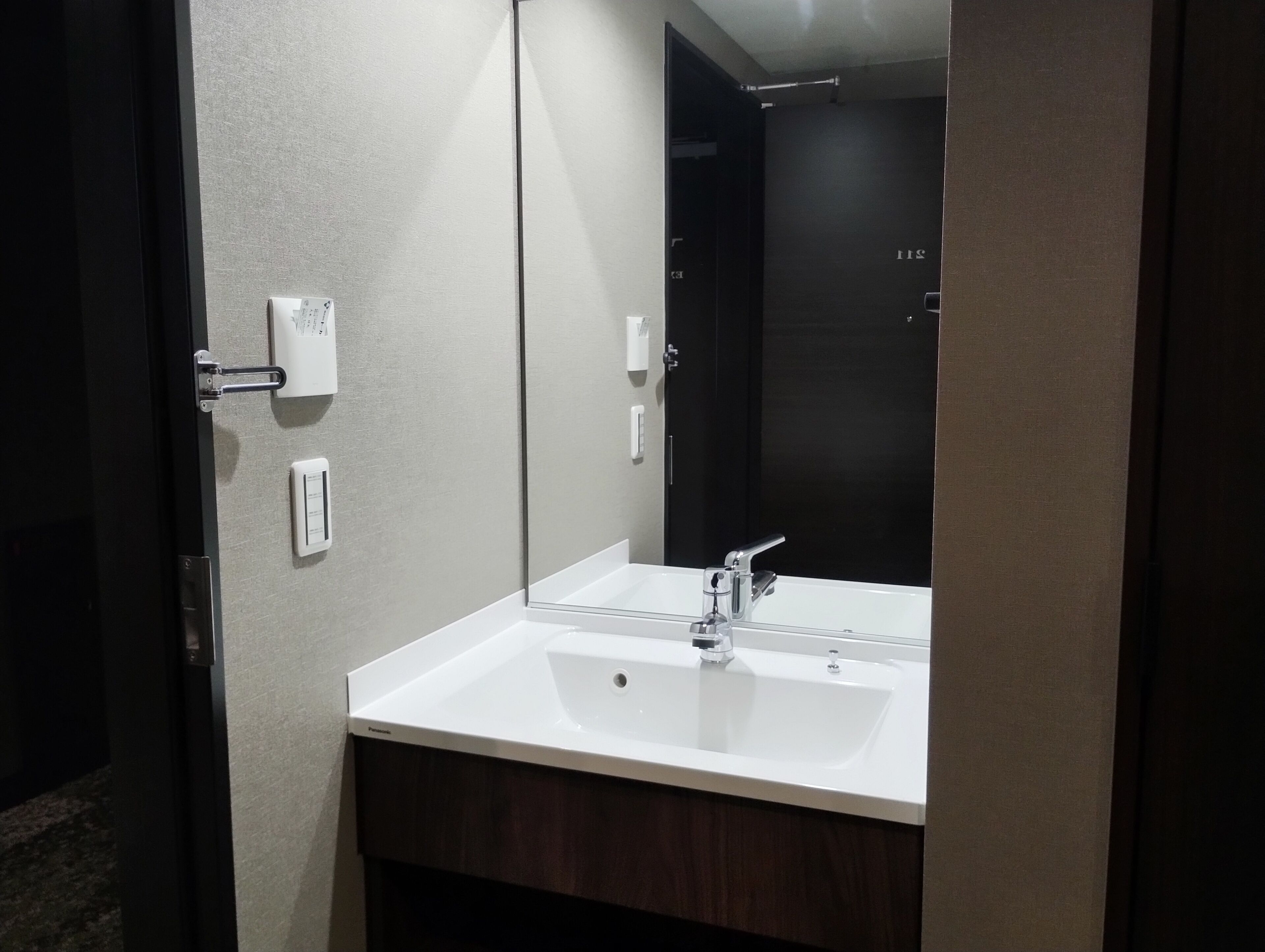 A bathroom with a white sink, a mirror, and a dark door.