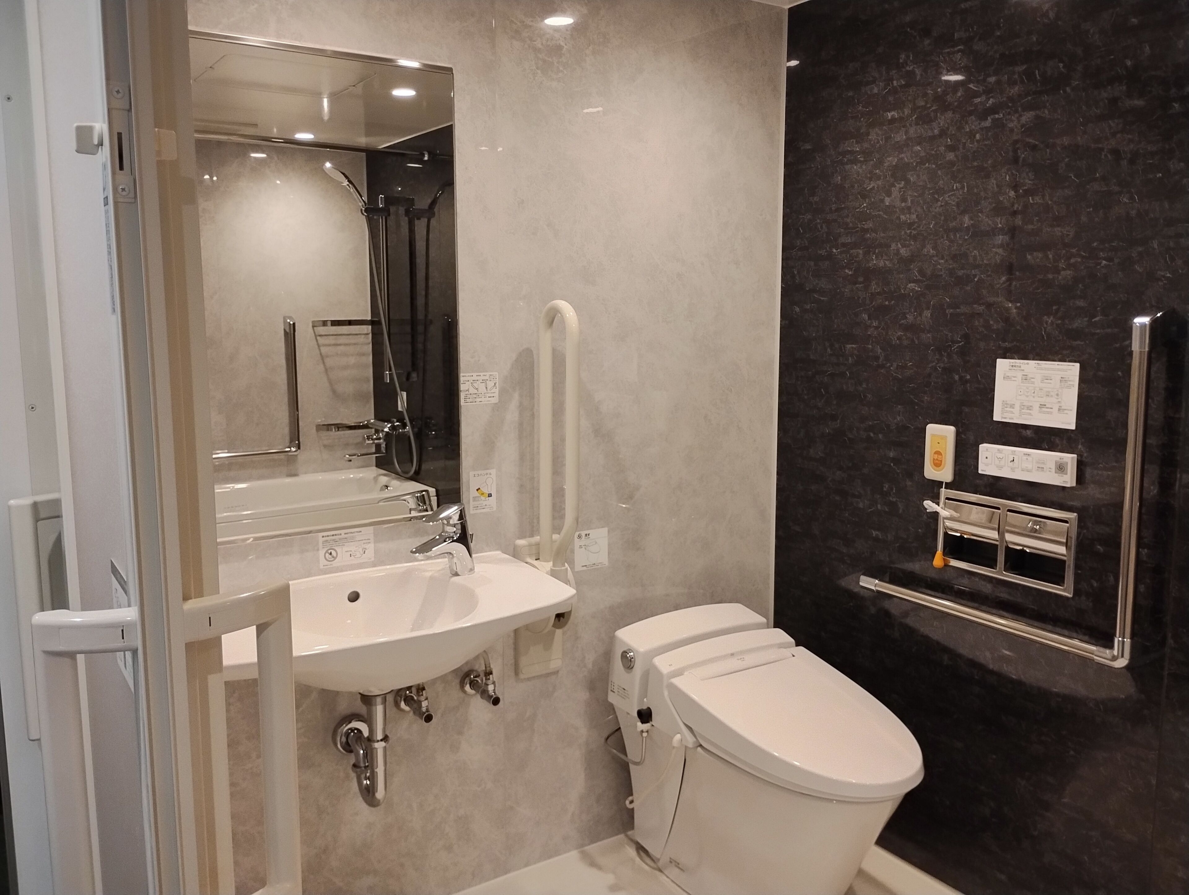 A modern bathroom with a sink, mirror, toilet, and a towel rack.