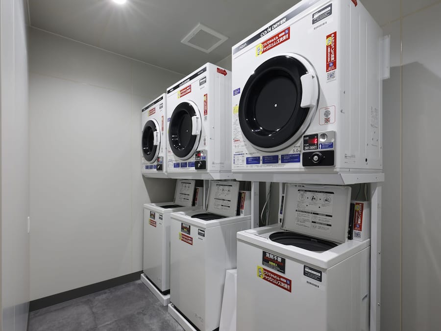 A laundry room with three stacked front-loading washing machines.