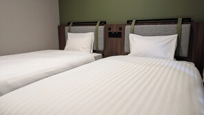 Twin beds with headboards, a control panel, and a green wall.