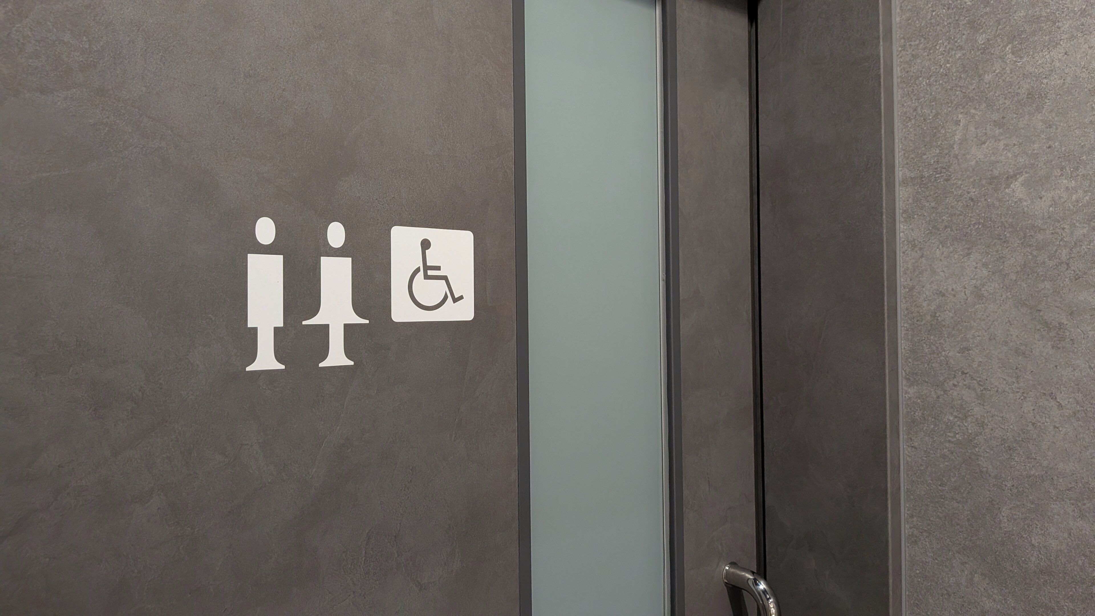 Baño con un letrero que indica baños de hombres y de mujeres, y el símbolo de acceso para discapacitados.