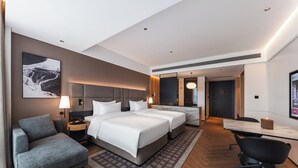 Una habitación de hotel moderna con una cama grande, un escritorio, una silla y un sofá.