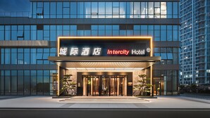 Una entrada de hotel moderna con un cartel llamativo, amplias ventanas y una fachada bien iluminada.