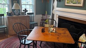 A dining room with a wooden table, chairs, a fireplace, and a ceiling fan. - Step Back in Time, Relax in Modern Comfort (Camden)