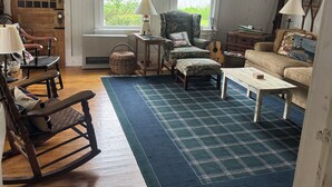 A cozy room with a wooden ceiling, a rocking chair, a sofa, a coffee table, and a patterned rug. - Step Back in Time, Relax in Modern Comfort (Camden)
