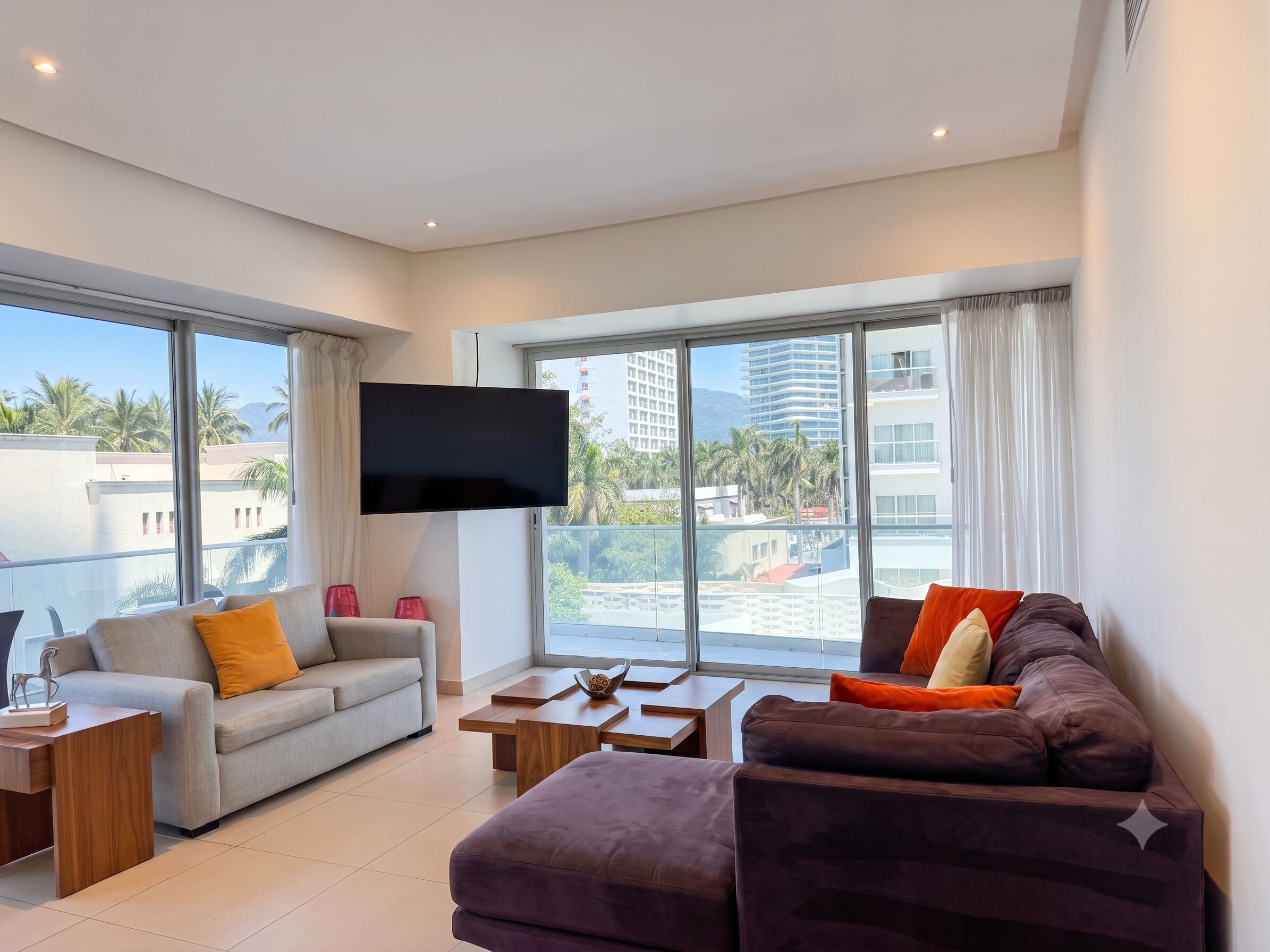 A modern living room with a sofa, a coffee table, and a flat-screen TV mounted on the wall.