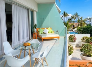 A balcony with a glass table, white chairs, a sofa with cushions, and potted plants. - ICON Oceanview Retreat by Monyxbnb (Puerto Vallarta)