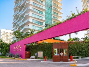 A modern hotel entrance with a prominent pink archway, a wooden bench, and a security gate. - ICON Oceanview Retreat by Monyxbnb (Puerto Vallarta)