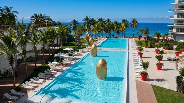 A resort pool with lounge chairs and palm trees, overlooking the ocean. - ICON Oceanview Retreat by Monyxbnb (Puerto Vallarta)