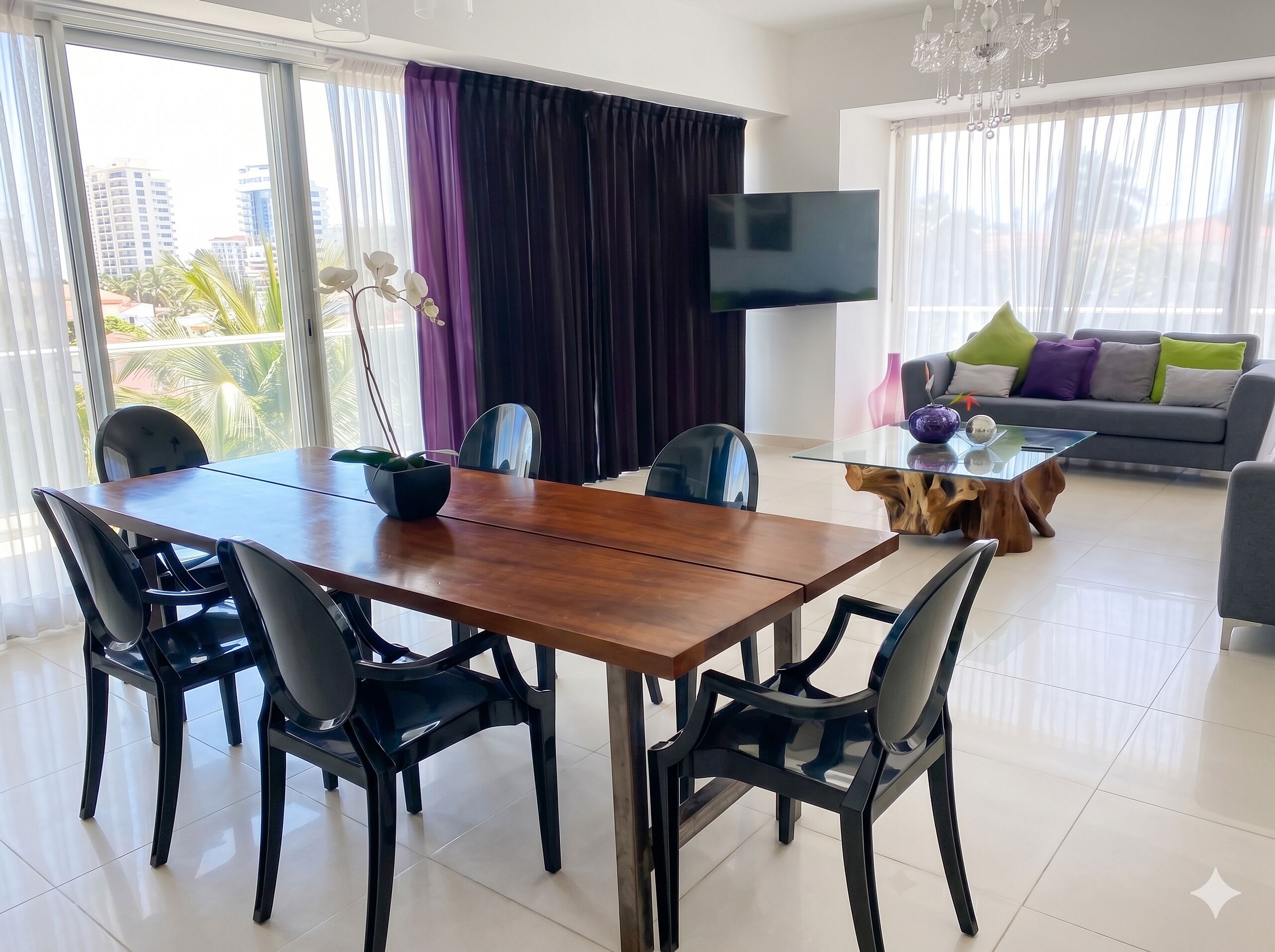A modern living room with a dining table, chairs, a sofa, a TV, and large windows with curtains.