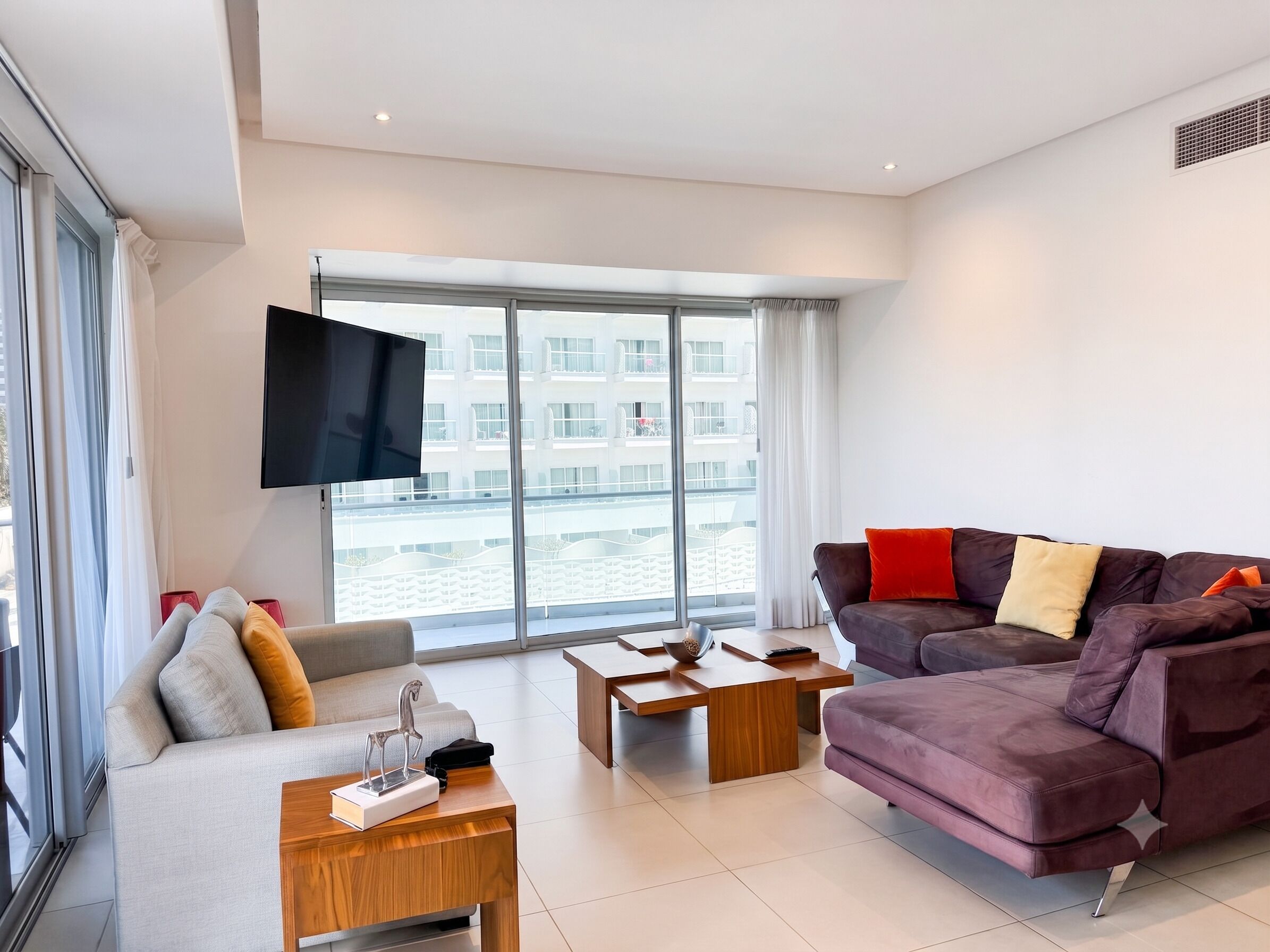 A modern living room with a sofa, coffee table, and a flat-screen TV mounted on the wall.