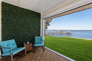 Un balcon donnant sur un lac, deux chaises, une petite table et un mur végétal.