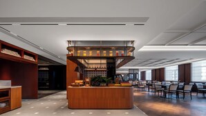 Un área de bar moderna con barra de madera, asientos y vista al salón.