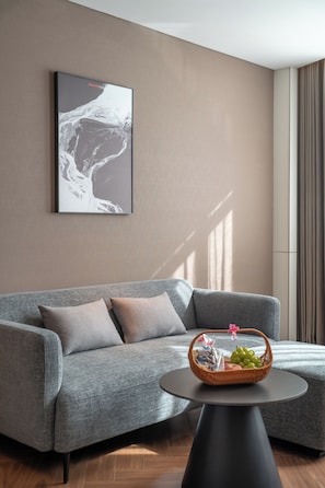 Una sala de estar moderna con un sofá gris, una mesa de centro redonda con una cesta, y una obra de arte enmarcada en la pared.
