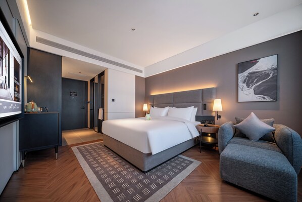 Ett modernt hotellrum med en stor säng, sängbord, en soffa och en tv.