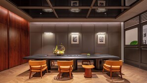 Un salón de conferencias con una larga mesa, cuatro sillas y un centro de mesa decorativo.