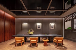 Un salón de conferencias con una larga mesa, cuatro sillas y un centro de mesa decorativo.
