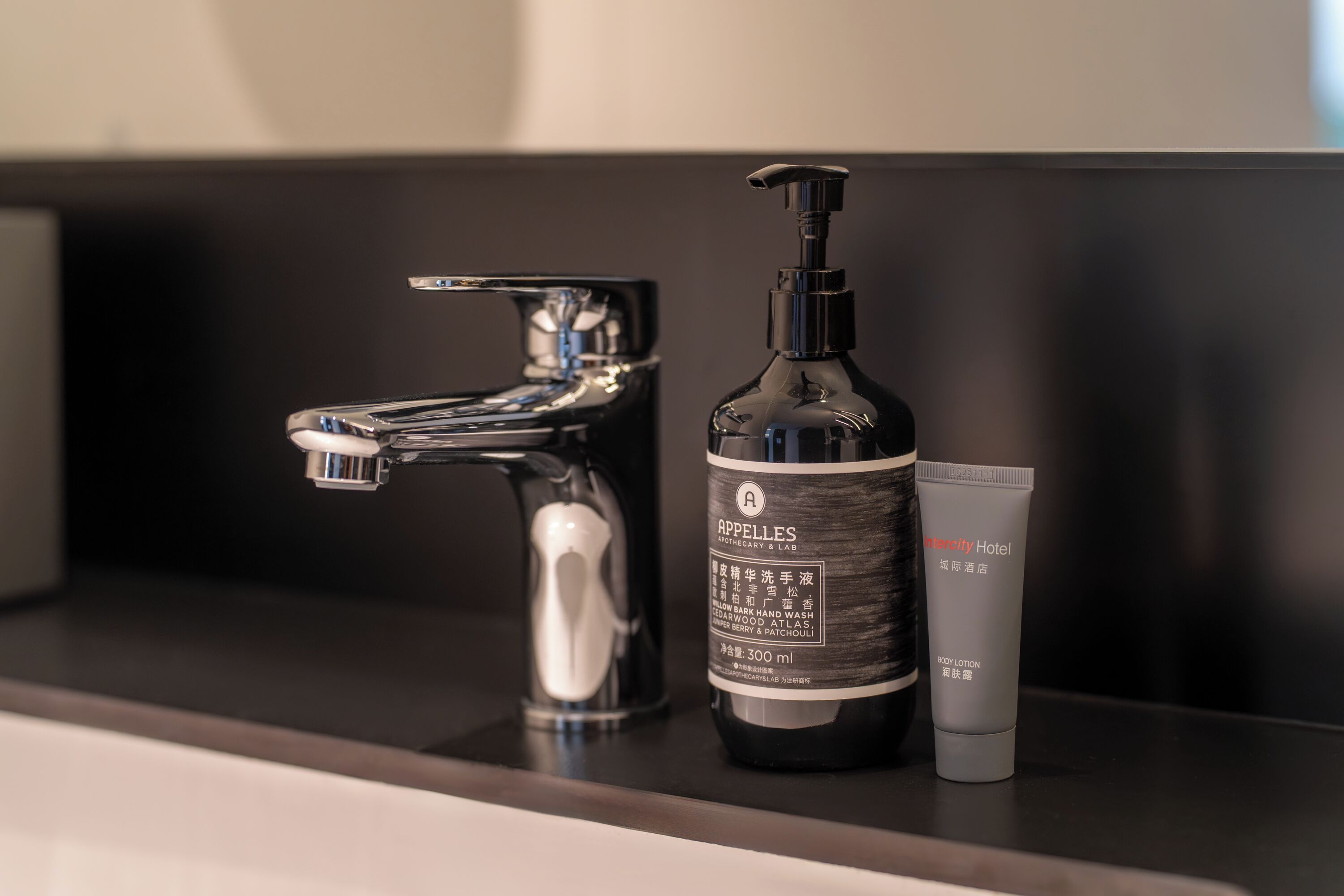 A bathroom sink with a modern faucet, a bottle of body lotion, and a tube of cream.