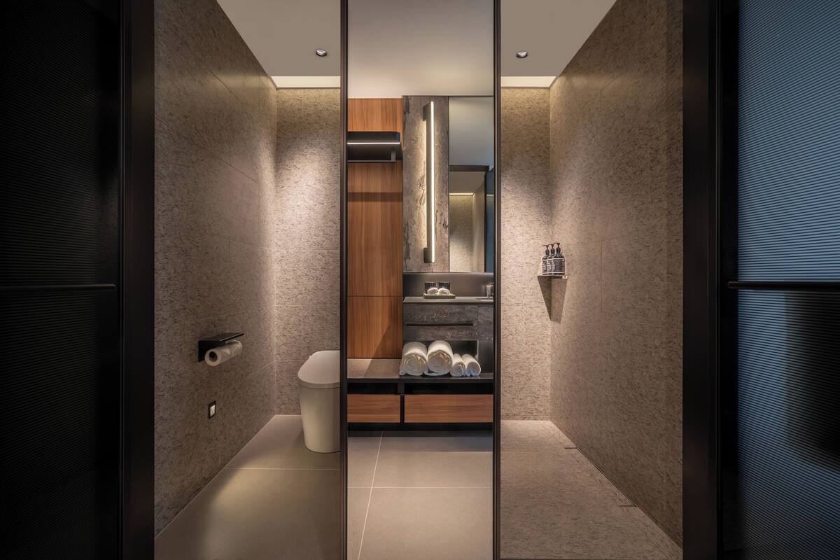 Un baño moderno con inodoro, lavamanos y espejo.