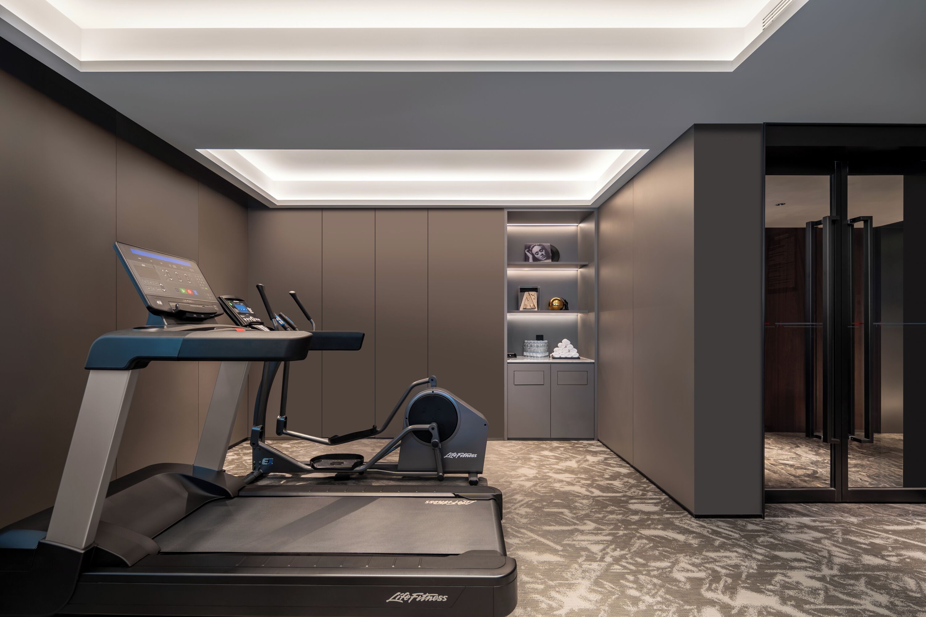 Un gimnasio moderno con cinta de correr, elíptica y banco de pesas.