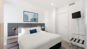 A hotel room with a bed, bedside tables, a TV, and a framed picture on the wall.