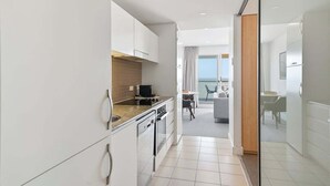 A modern kitchen with a view to the living area, a dining table, and a view of the sea.