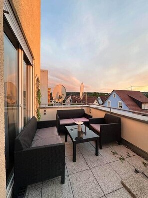 Une terrasse sur le toit, aménagée avec du mobilier d’extérieur, une antenne parabolique et offrant une vue sur les maisons voisines.