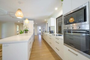 A modern kitchen with white cabinetry, a built-in oven, and pendant lighting. - Endless Summer Stay, Noosa Heads (Noosa Heads)