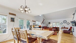 Ein geräumiger Wohnbereich mit einem Holzesstisch, Stühlen, einer Couch und einem Kamin.