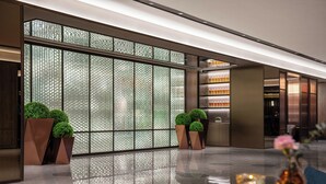 Un vestíbulo moderno con piso reflectante, grandes divisiones de vidrio y plantas en macetas.