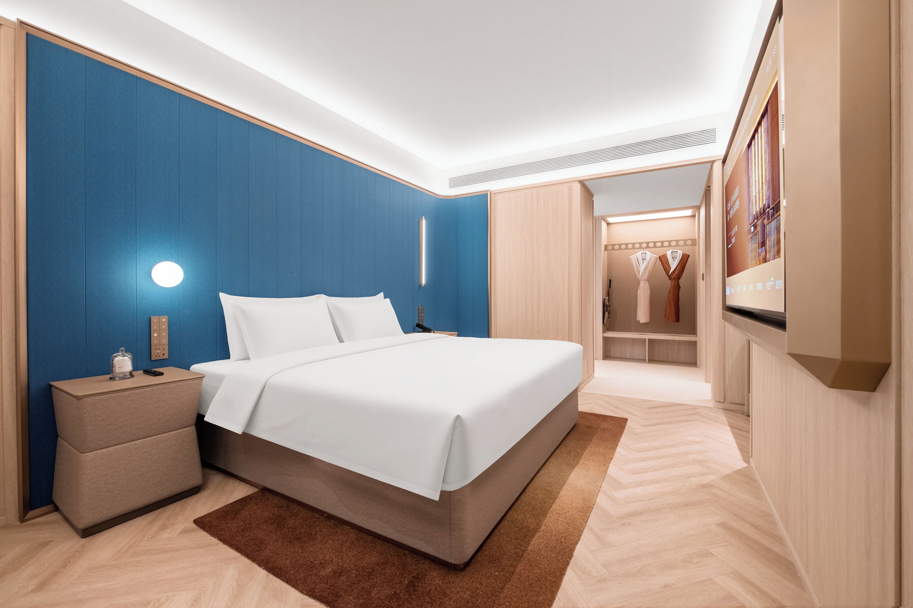 A modern bedroom with a bed, bedside tables, a nightstand, a wardrobe, and a mirror.
