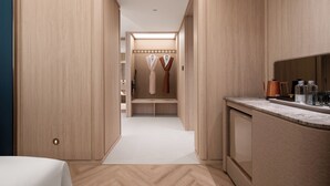 Habitación de hotel con armario de madera, tocador empotrado con espejo y zona de estar con banco.