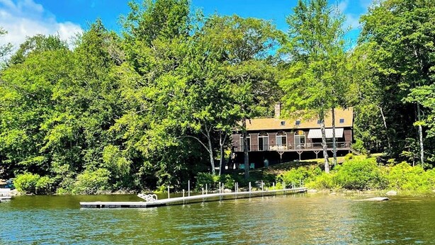 Una cabana al costat d'un llac amb un moll, envoltada de boscos densos.