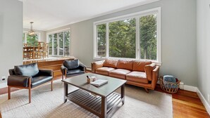 Ein geräumiges Wohnzimmer mit großem Fenster, einer Couch, einem Couchtisch und einem Essbereich.