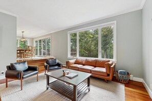 Ein geräumiges Wohnzimmer mit großem Fenster, einer Couch, einem Couchtisch und einem Essbereich.