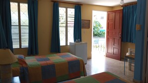 A room with a bed, a desk, a refrigerator, and a door leading outside. - CasaSylvie (Sosua)