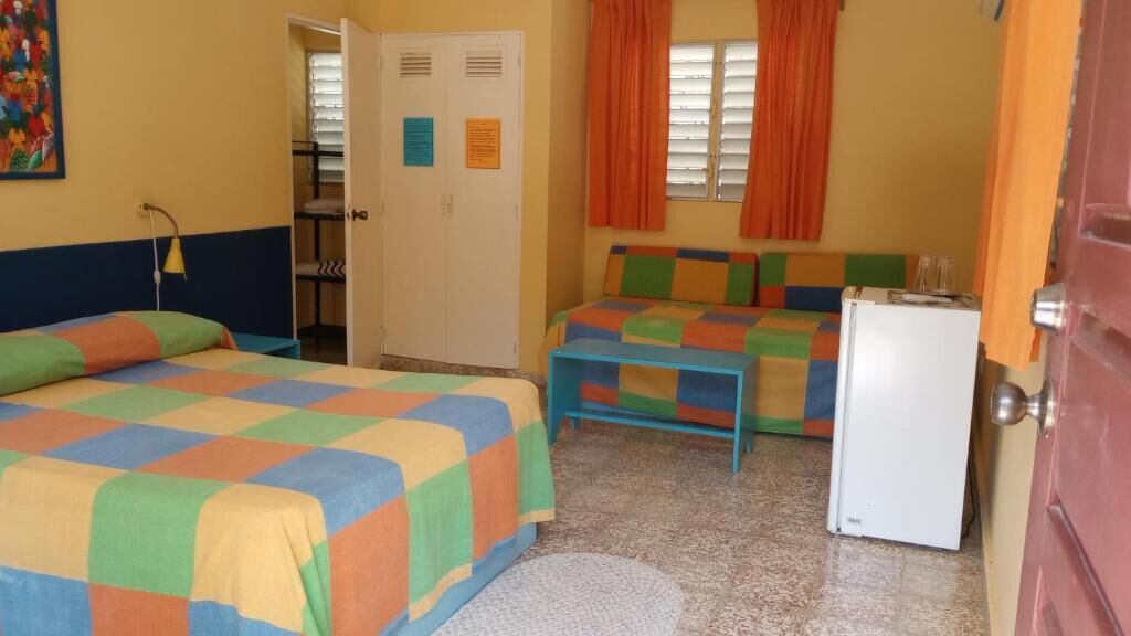 A room with two beds, a small refrigerator, and a door leading to another room.