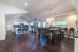 A spacious kitchen with wooden flooring, a dining area with a chandelier, and a view through a window. - Private Beach Access + Hot Tub / Near Wineries / Lake Erie Retreat / Sleeps 12 (North East)