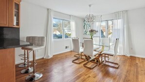 A modern kitchen with a dining area, wooden flooring, and large windows. - Comfortable 3BR • Complimentary Parking • Minutes from NYC • Ideal for Groups (White Plains)