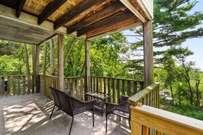 A wooden deck with a glass table and chairs, surrounded by trees. - 6BR · Game Room · Free Parking · Near Stadiums (Pittsburgh)