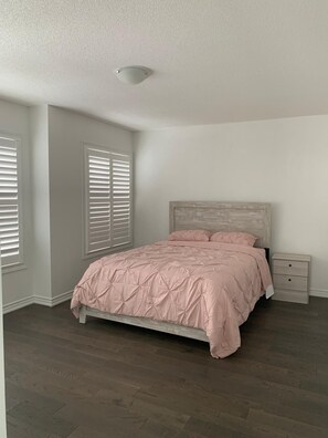 A bedroom with a bed, a nightstand, and a window with blinds. - Enjoy the comfort of this cozy home, minutes away from downtown! (Kawartha Lakes)