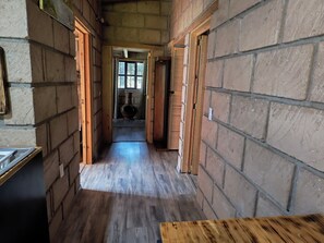 Un couloir étroit avec un plancher en bois, des murs en pierre et une table en bois au fond.