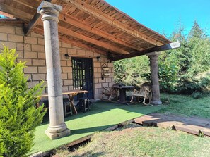 Une cabane rustique avec une façade en pierre, une véranda en bois, une table et des chaises.