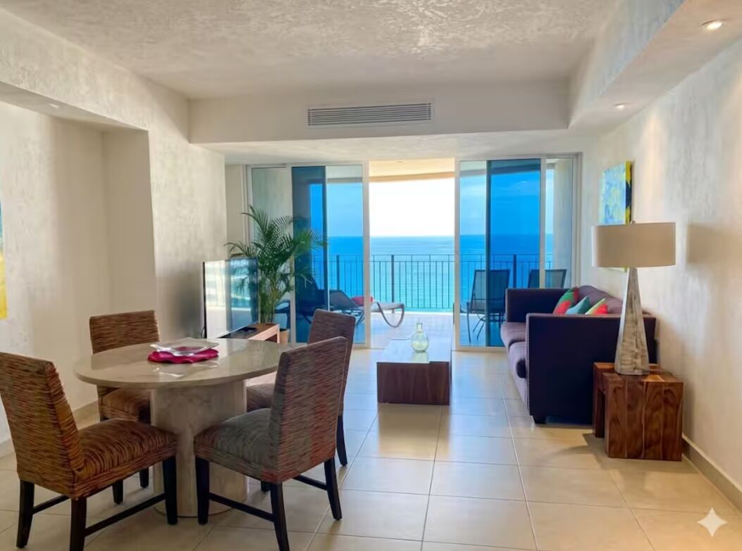 A spacious living area with a balcony, a dining table, and a sofa.