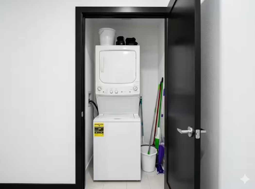 Une petite pièce équipée d’un lave-linge, d’un four à micro-ondes et de produits de nettoyage.
