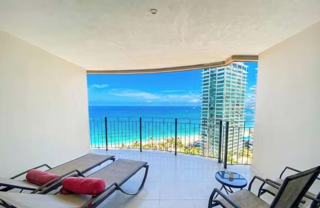 Un balcon avec vue sur l’océan et un immeuble de grande hauteur.