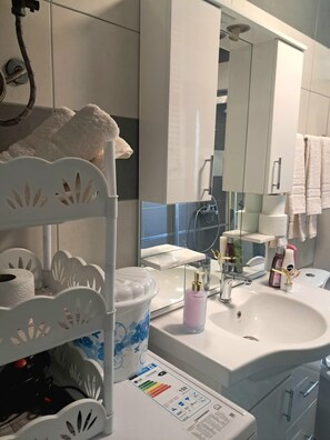 A bathroom with a white sink, a mirror, a towel rack, and a toilet paper holder. - Gorgeous 1-bedroom apartment with AC in lively Prishtinë (Prishtinë)
