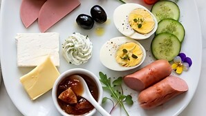 En tallerken med forskelligt mad, herunder brød, tomater, agurker, æg, ost og kød.