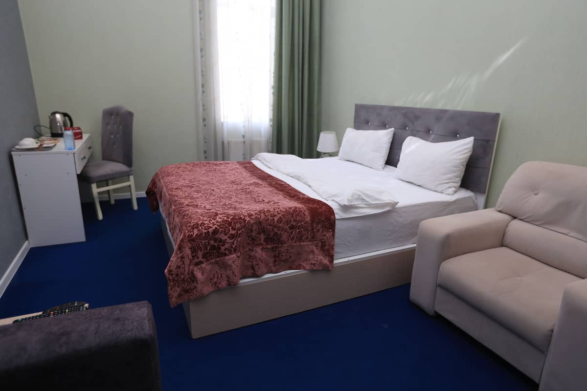 Una habitación de hotel con cama, escritorio, silla y sofá.