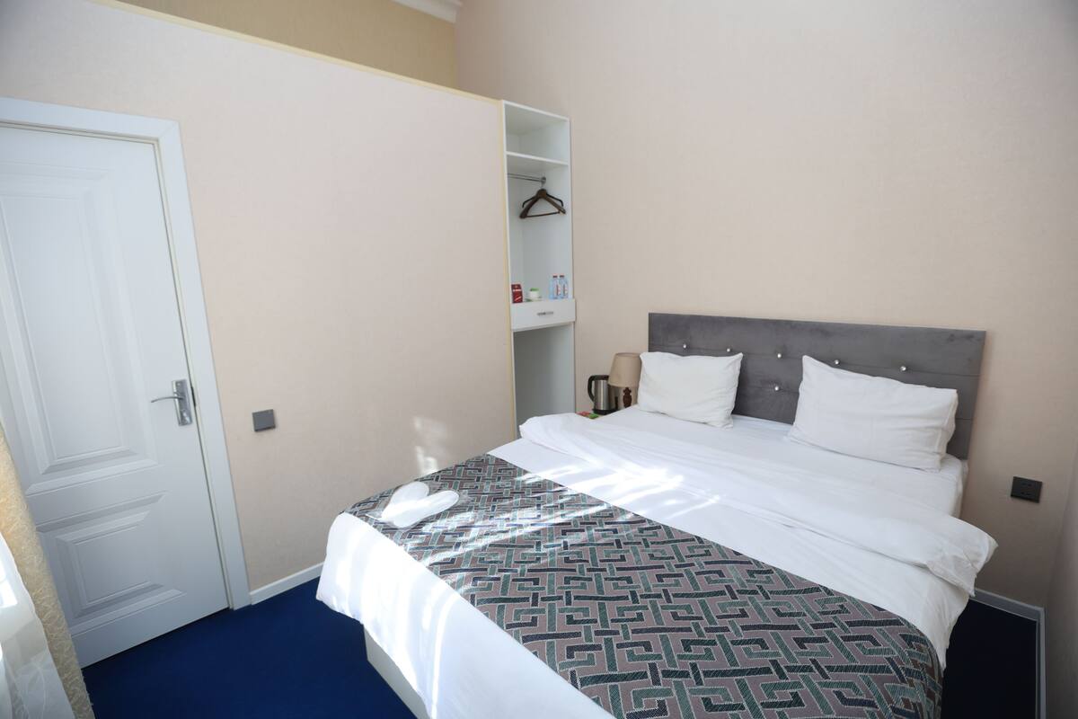 Una habitación de hotel con una cama, un armario y una repisa con artículos de aseo.